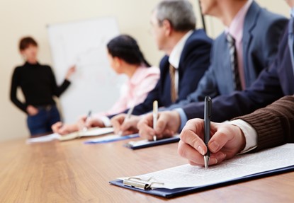 Row of business people making notes during presentation